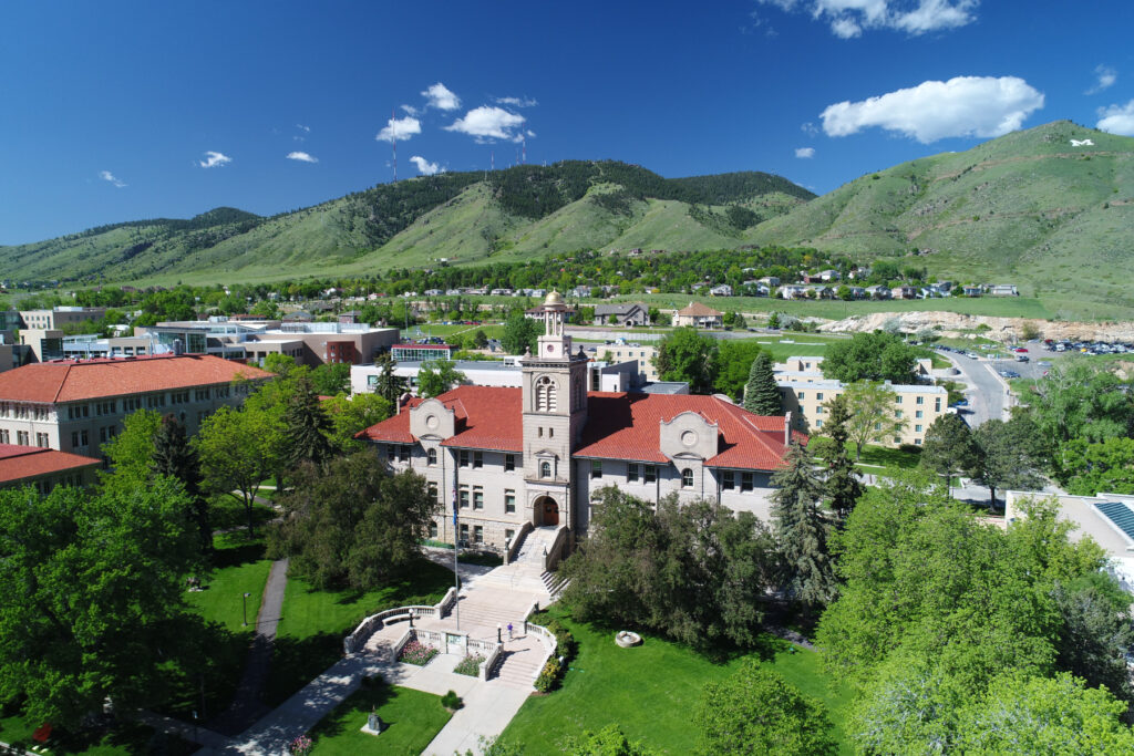 Aerial drone shot of public buildings, with green hills and blue sky in background. Shot by American /Video Documentation.