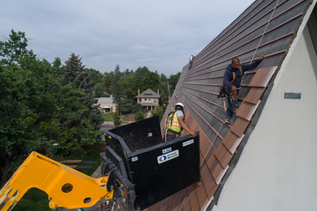 Aerial drone shot of roofers working on a very steep roof, shot by American Video Documentation.